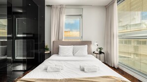 A modern hotel room with a large bed, a view of the city, and a glass partition. - Rooftop Jacuzzi Penthouse by Sea N' Rent (Haifa)