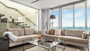 A modern living room with a beige sofa, a glass coffee table, and a view of the ocean. - Rooftop Jacuzzi Penthouse by Sea N' Rent (Haifa)