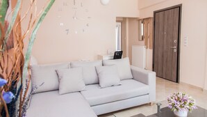 Una sala moderna con un sofá gris, un reloj de pared y una puerta.
