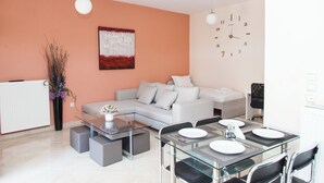 Una sala de estar moderna con un sofá, una mesa de centro de vidrio y un comedor con sillas y una mesa preparada para cuatro.