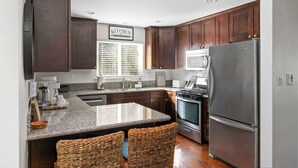 A modern kitchen with dark wood cabinets, a stainless steel refrigerator, and a granite countertop.