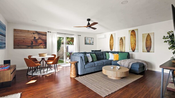 A modern living room with a blue sofa, wooden coffee table, and a ceiling fan.