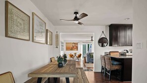 A modern kitchen with wooden cabinets, a dining area with a wooden table and benches, and a ceiling fan.