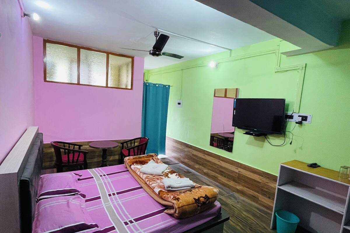 A room with a bed, a desk, a chair, a television, and a mirror.