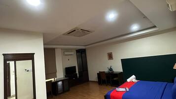 Une chambre d’hôtel comprenant un lit, un bureau, une chaise, une télévision et un miroir.