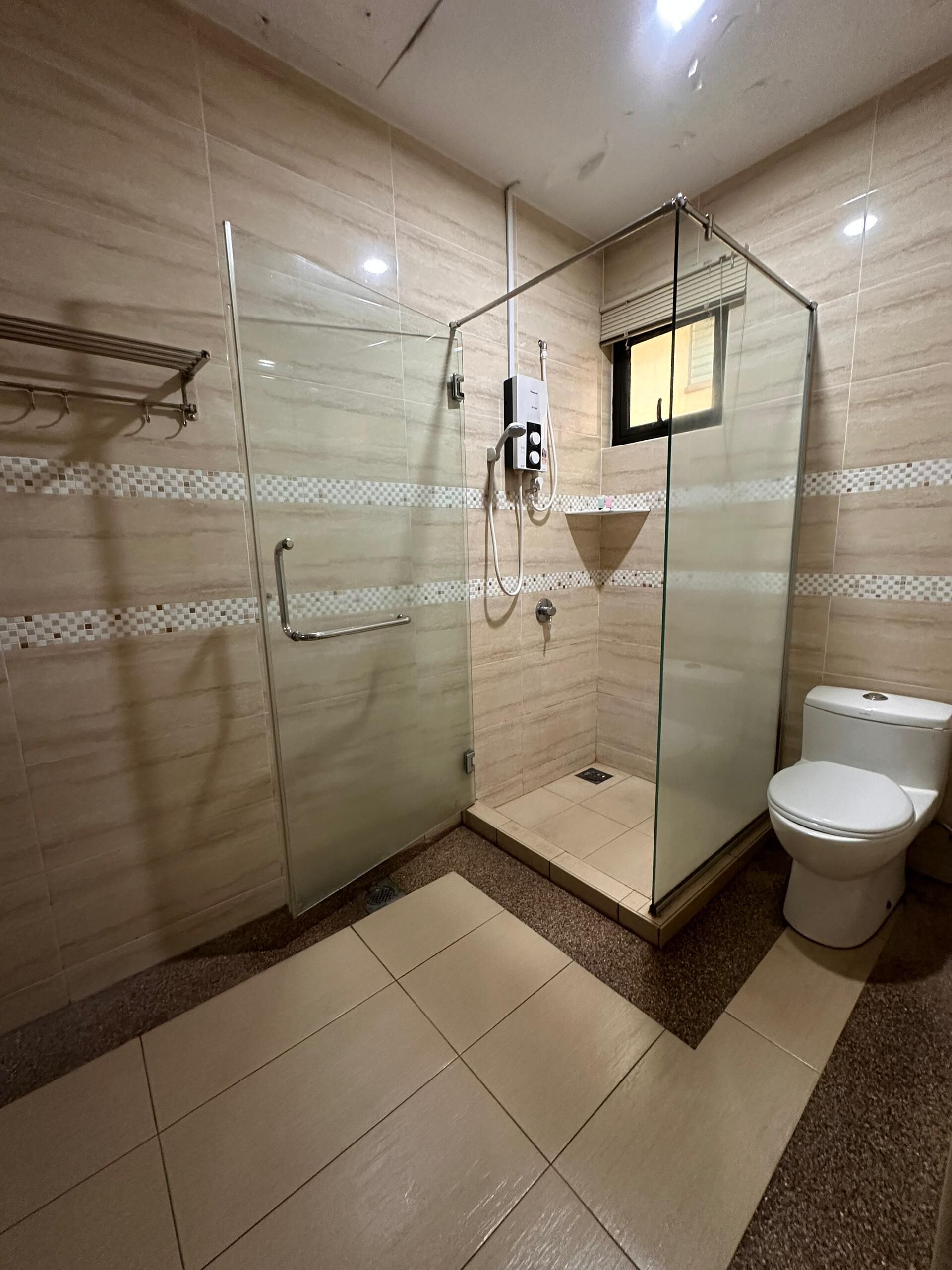 A modern bathroom with a glass-enclosed shower, a toilet, and a tiled floor.