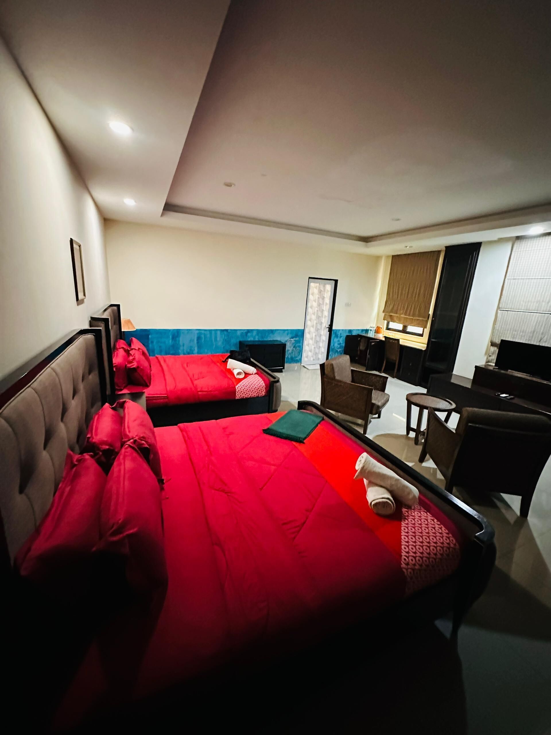 Quarto de hotel com duas camas, uma escrivaninha, uma cadeira e uma televisão.