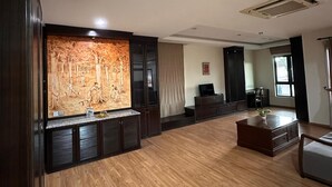Un salón espacioso con piso de madera, armarios de madera oscura, un televisor de pantalla plana y un cuadro grande en la pared.