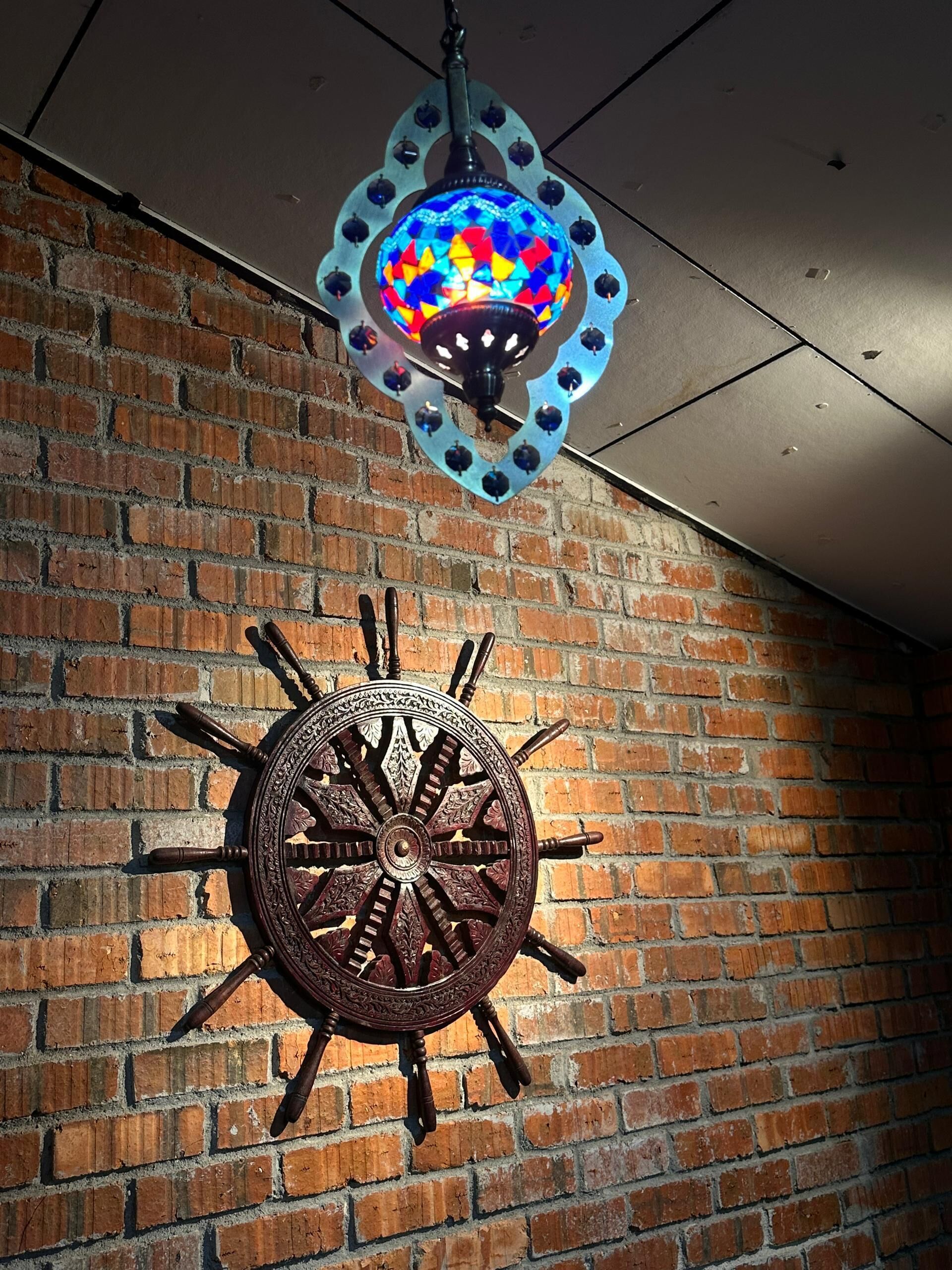 Un reloj de pared decorativo con motivos de sol y una lámpara colgante de vitral.