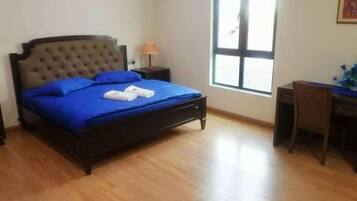 A bedroom with a bed, a desk, a chair, a window, and a lamp.