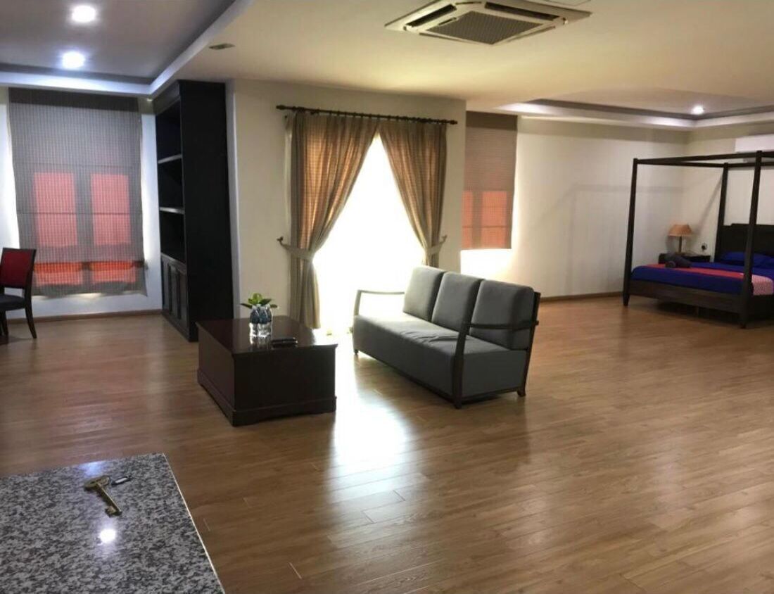 A living room with a sofa, a coffee table, a TV, and a bed with a canopy.