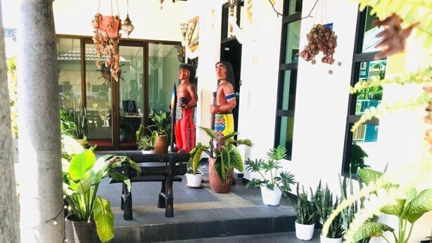 Un patio con plantas en macetas, un banco y dos estatuas.