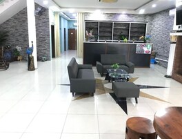 Un vestíbulo amplio con mostrador de recepción, zona de estar y una escalera.