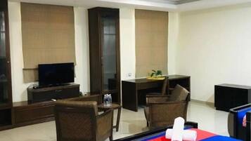 A hotel room with a bed, a desk, a chair, a television, and a minibar.