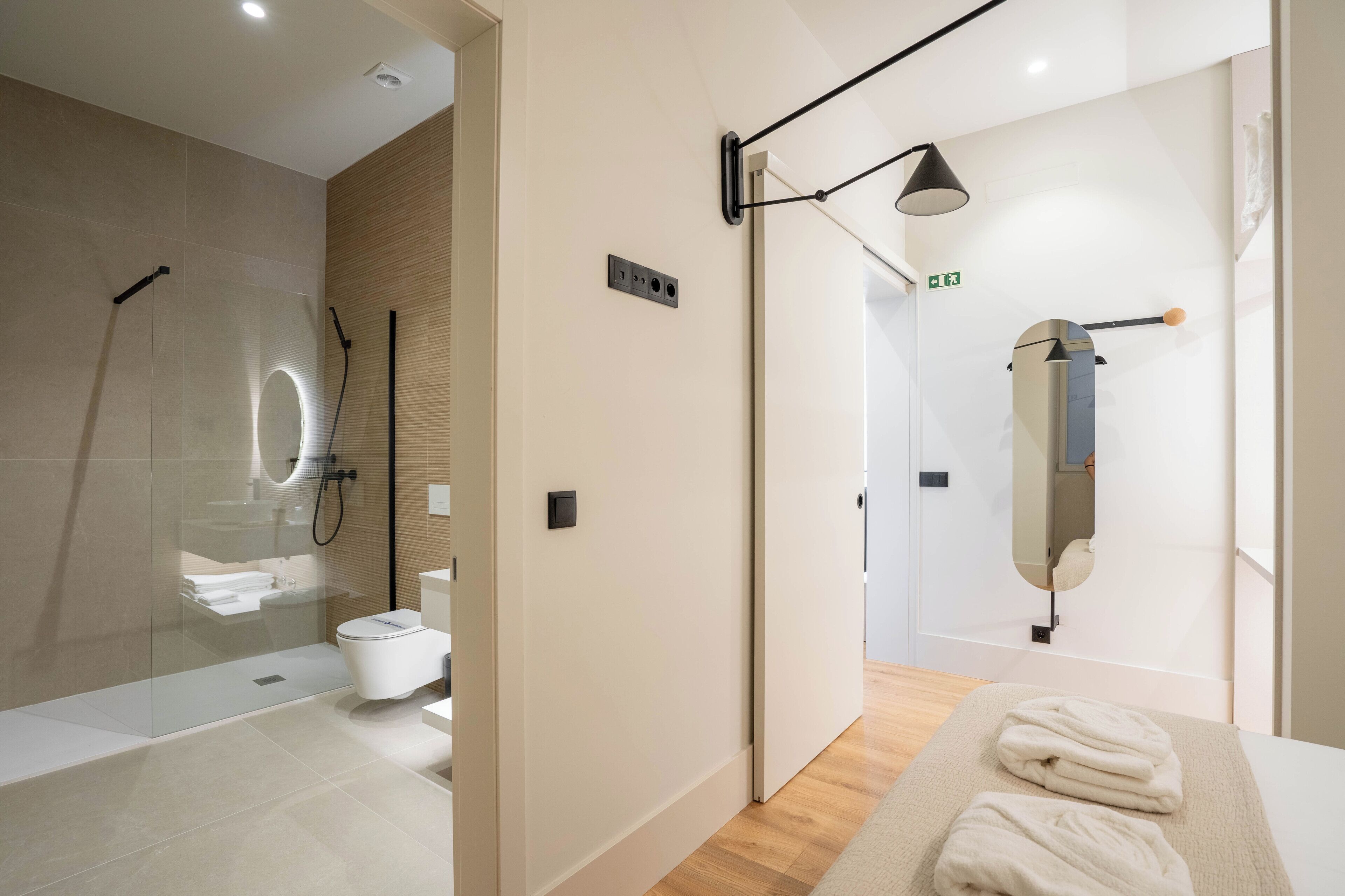 A modern bathroom with a glass-enclosed shower, a toilet, and a mirror.