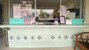 A reception desk with informational posters, a potted plant, and a wooden chair. - Hotel O De Anjung (Muadzam Shah)