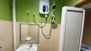 A bathroom with a white sink, a handheld showerhead, a wall-mounted soap dispenser, and a small mirror. - Hotel O De Anjung (Muadzam Shah)