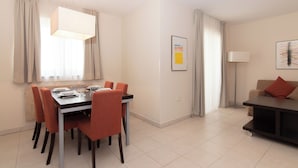 Un espace repas moderne avec une table et des chaises, un lampadaire et un canapé, le tout dans une pièce bien éclairée et agrémentée de rideaux.