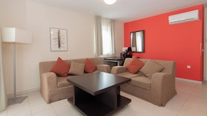 Un salon moderne avec deux canapés, une table basse, un lampadaire et un mur d’accent rouge.