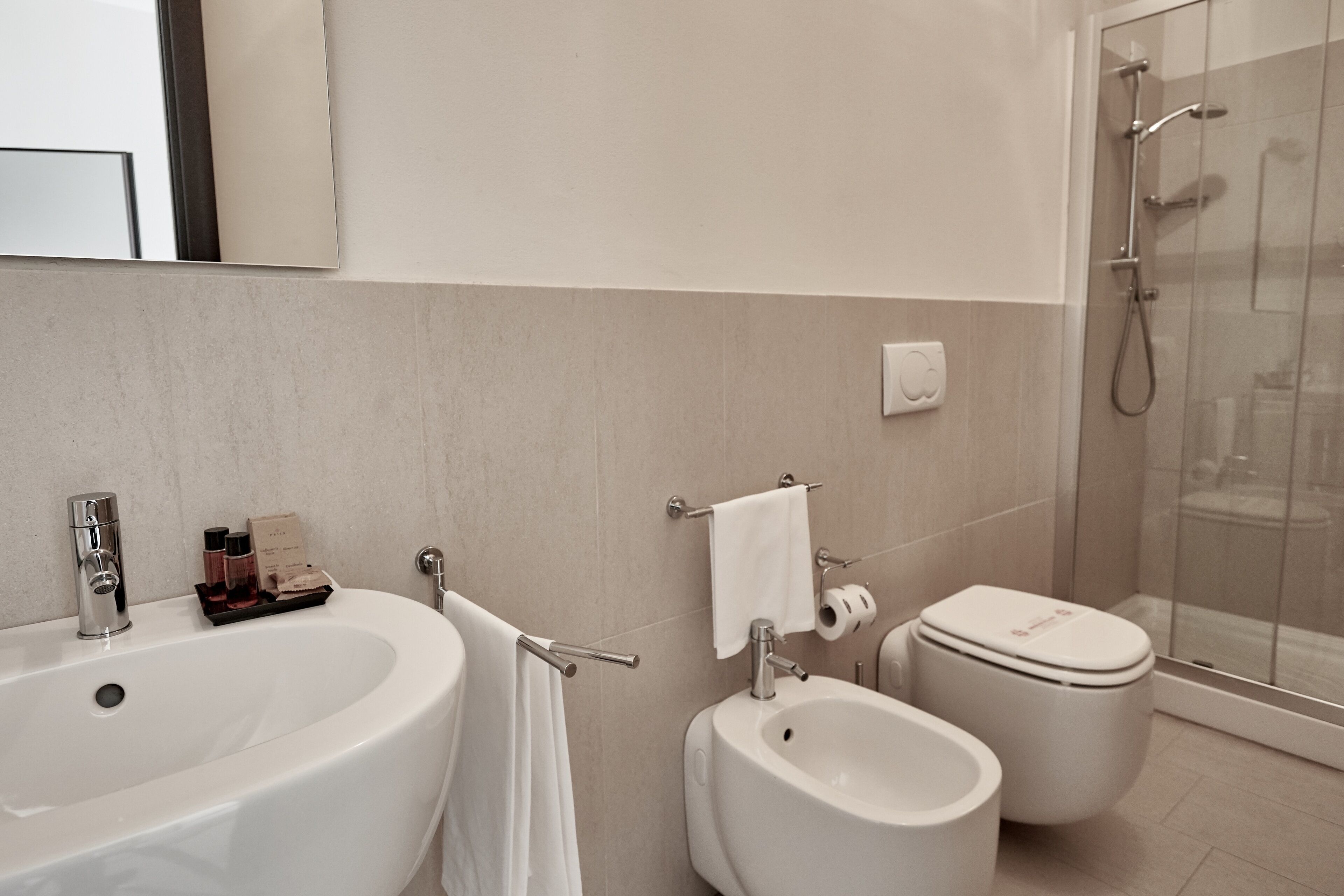 A modern bathroom with a large bathtub, a separate bidet, and a glass-enclosed shower.