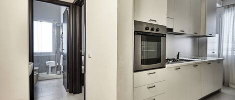 A modern kitchen with white cabinets, a built-in oven, and a stainless steel range hood.