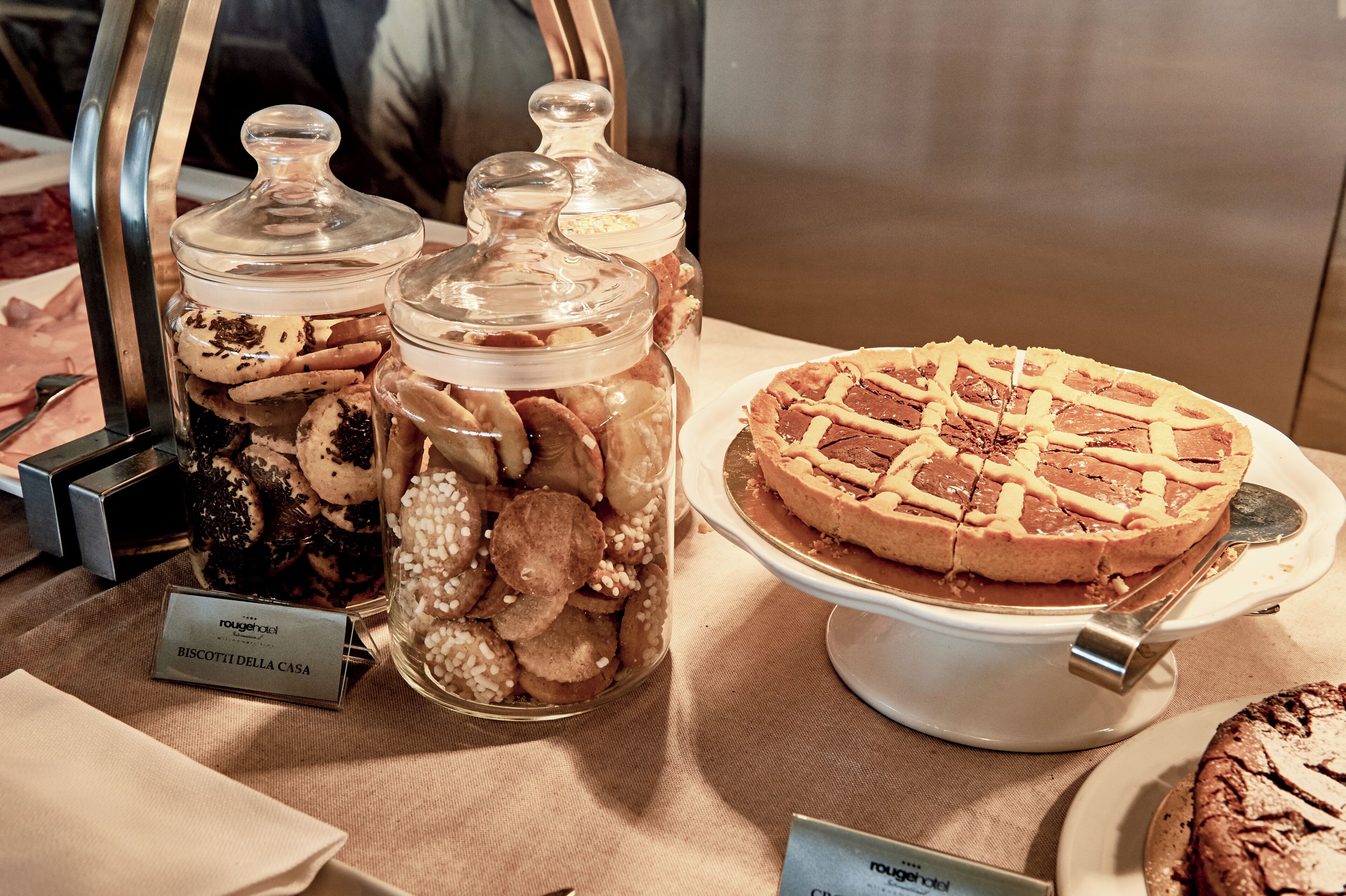 Uma mesa de buffet com potes de biscoitos e uma torta coberta com treliça.