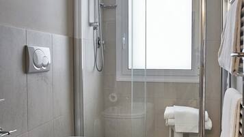 A modern bathroom with a glass-enclosed shower, a toilet, and a bidet.