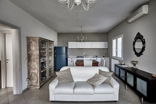 A modern kitchen with white cabinets, a blue refrigerator, and a chandelier.