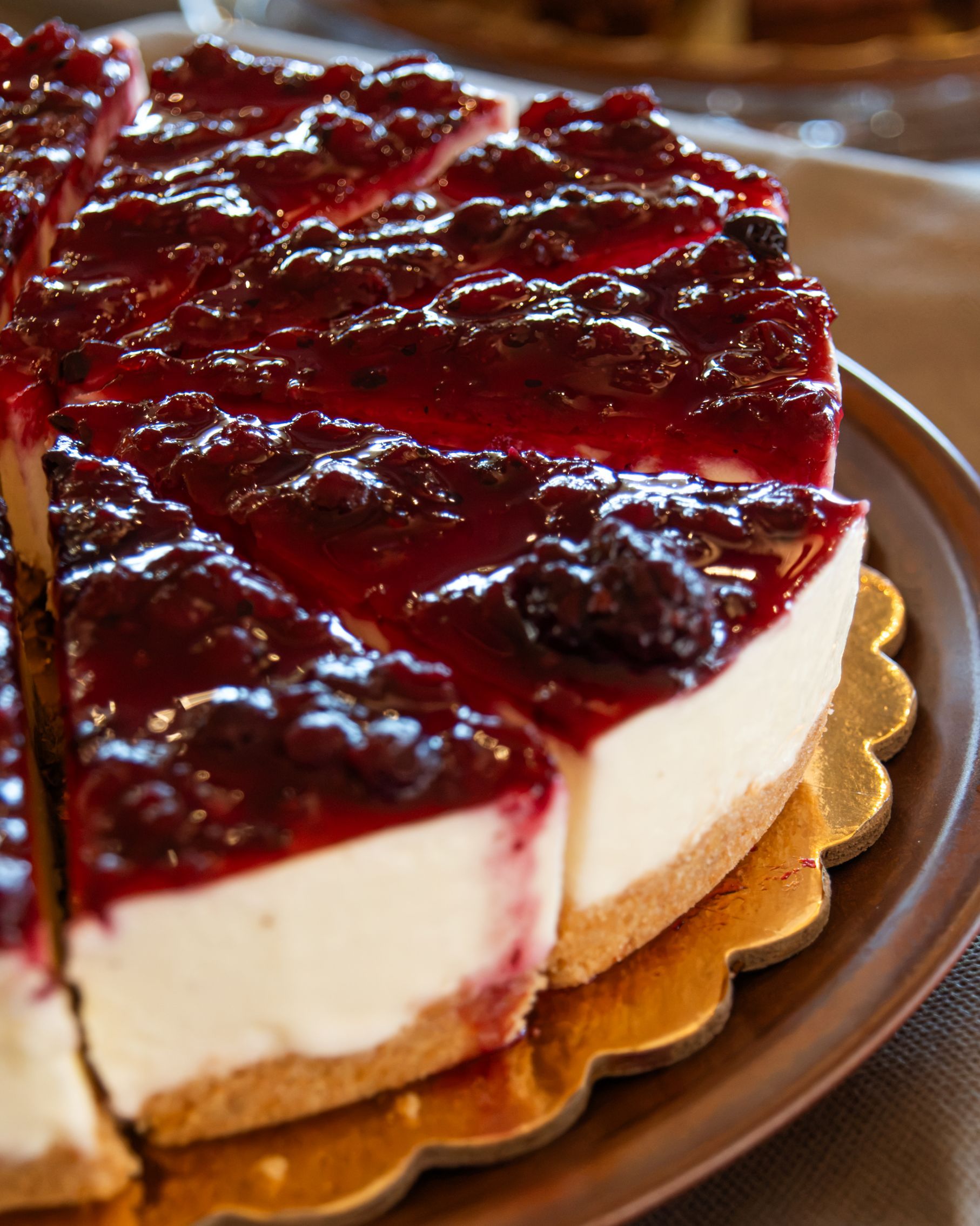 A pie with a red topping on a golden plate.