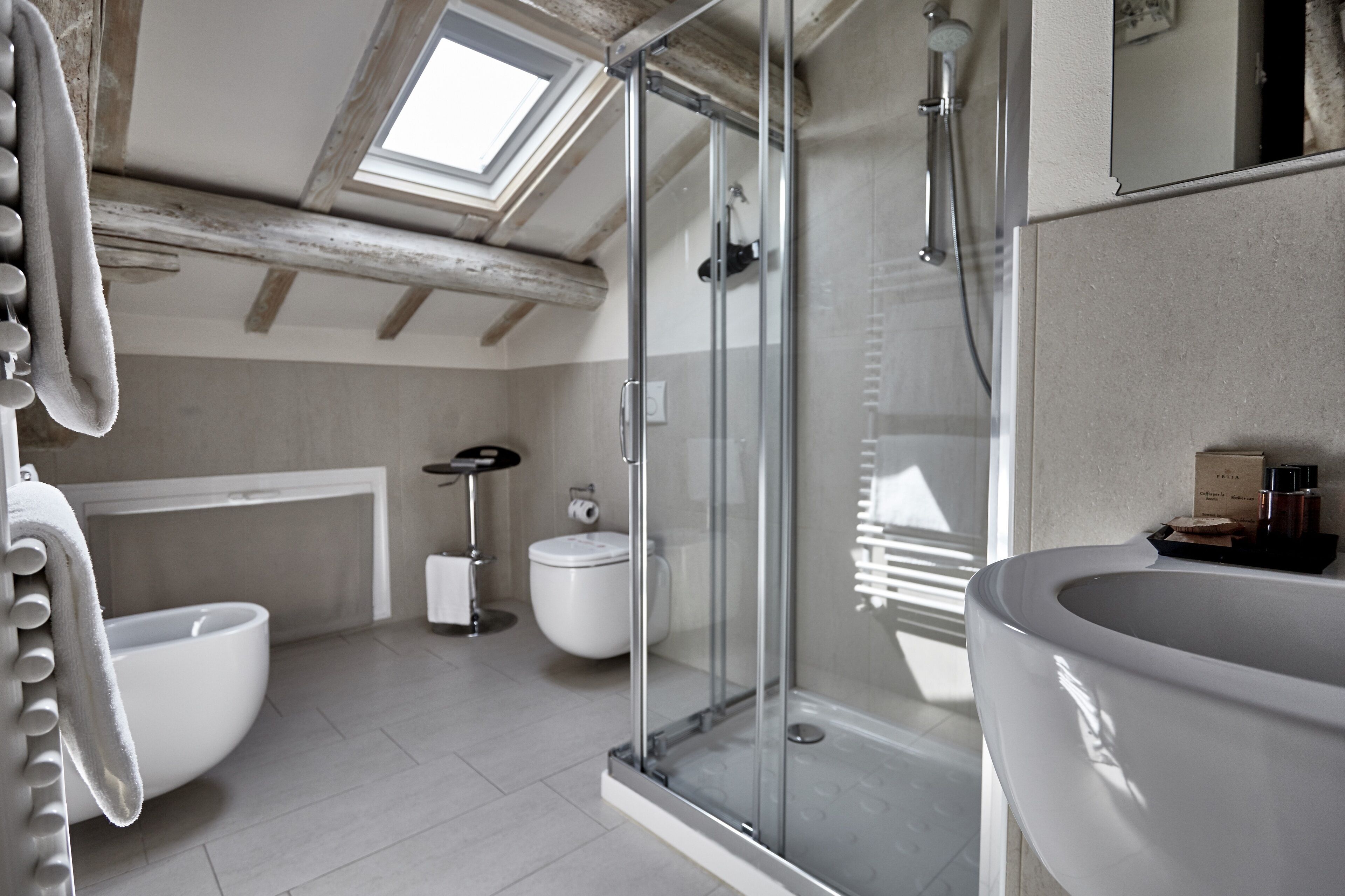 A modern bathroom with a skylight, a glass shower enclosure, a large bathtub, and a white sink.