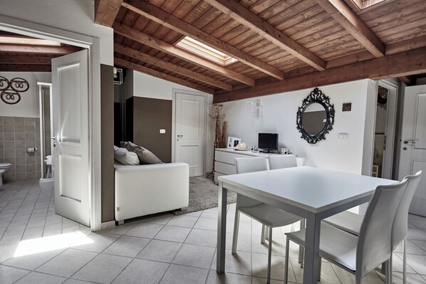 A modern kitchen with white appliances, a dining table, and a white sofa.