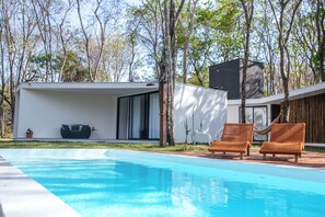 Relax by the rectangular pool surrounded by a well-manicured lawn and trees.