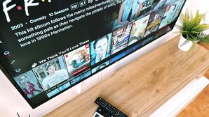 A television displaying a streaming service interface with multiple show options.