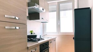 A modern kitchen with wooden cabinets, a gas stove, an oven, and a window with blinds.