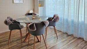 A dining area with a round table, chairs with fur trim, a hanging light fixture, and a wooden ceiling.