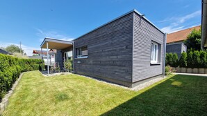 A modern house with a flat roof, a small attached garage, and a well-maintained lawn.