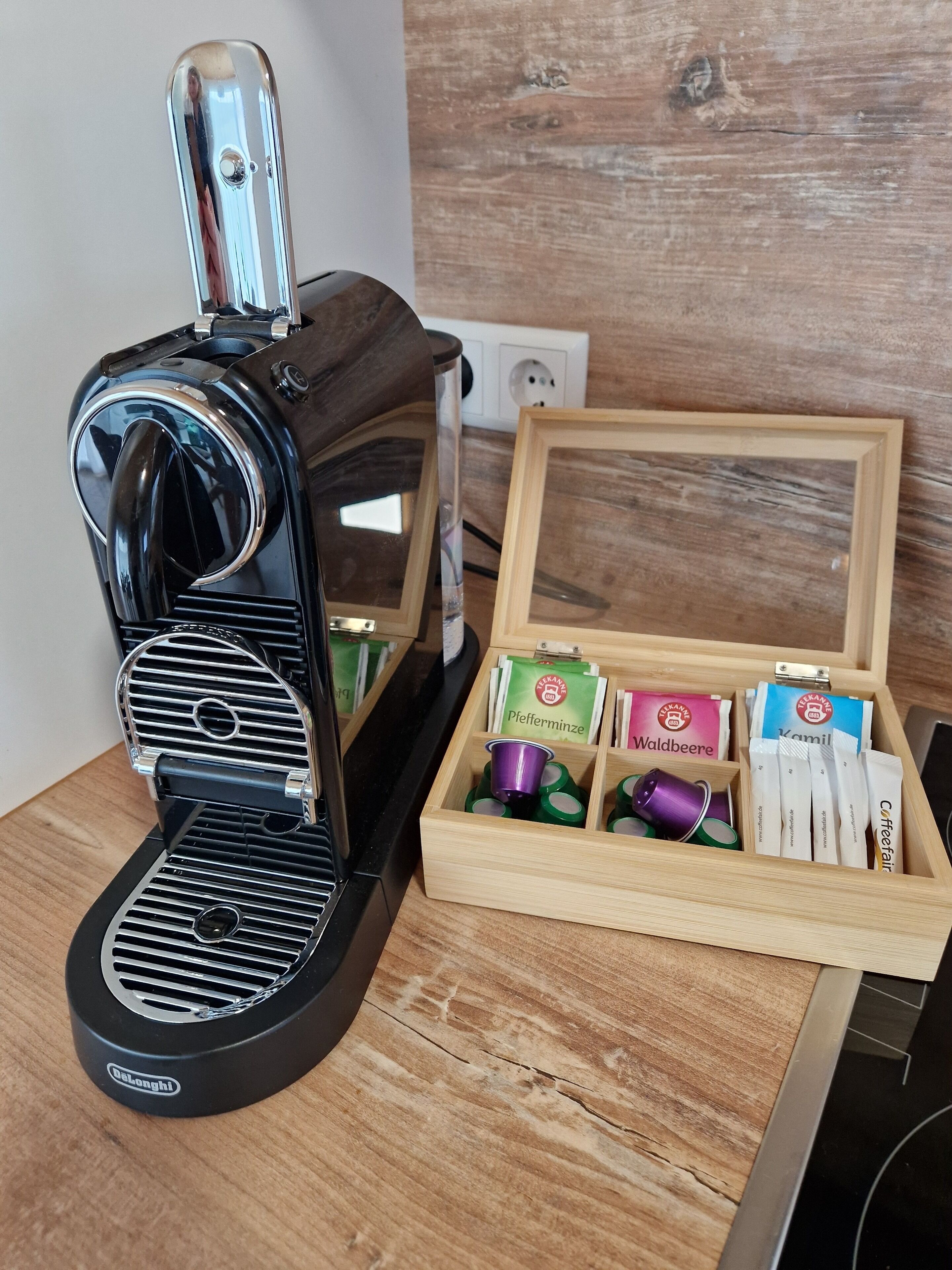 A coffee maker with a wooden box containing coffee pods and a tea box.