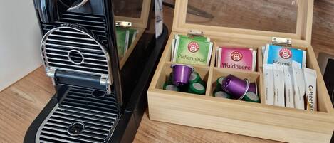 A coffee maker with a wooden box containing coffee pods and a tea box.