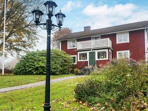 A red house with a green door, a white porch, and a black street lamp. - 6 Person Holiday Home in Lonashult (Lönashult)