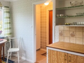 A kitchen with a wooden countertop, a white chair, and a shelf with decorative items. - 6 Person Holiday Home in Lonashult (Lönashult)