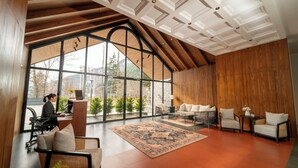 Una habitación amplia con un gran ventanal, techo de madera y una zona de estar con una mesa de centro.