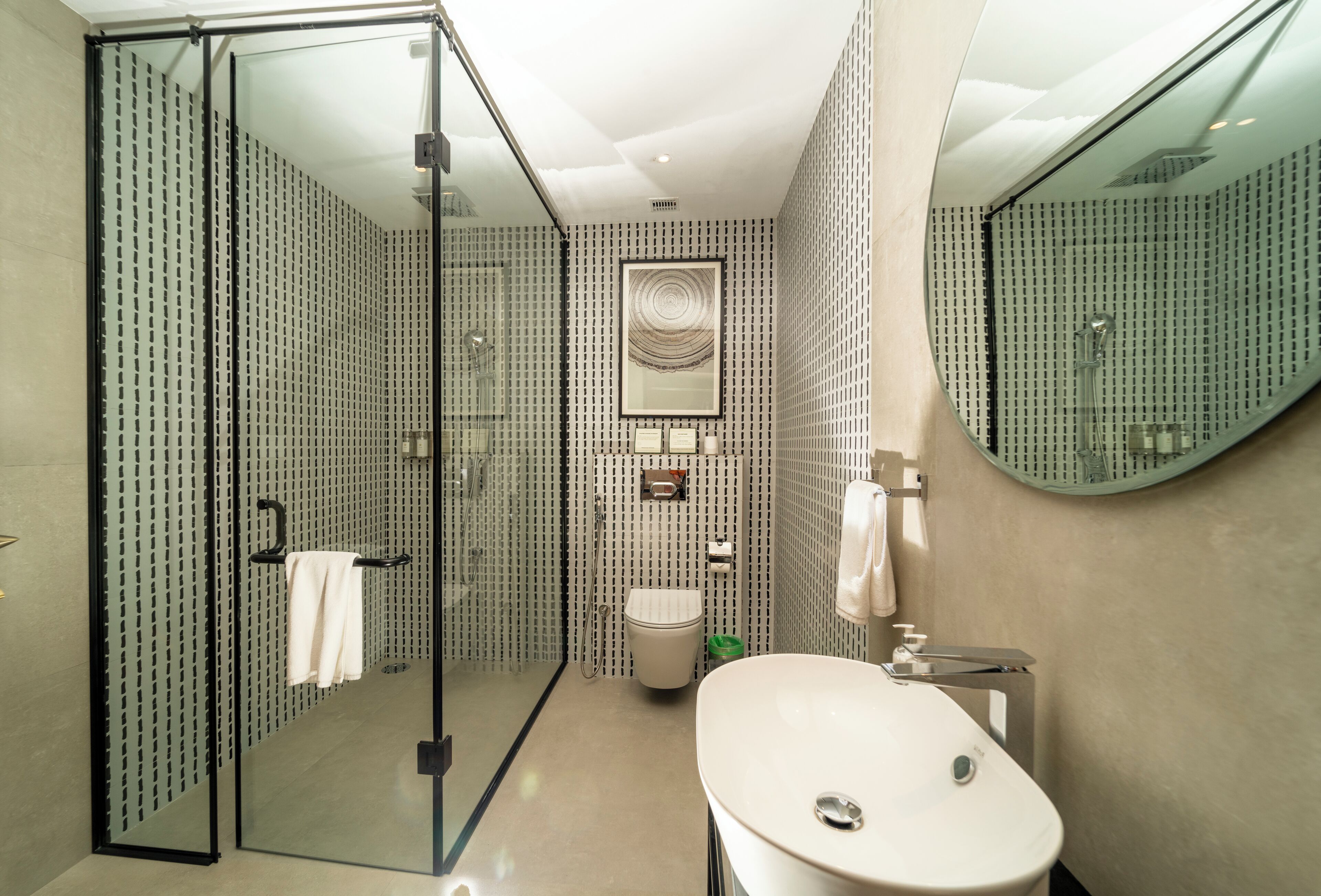 Un baño moderno con cabina de ducha de vidrio, un lavamanos blanco y un espejo grande.