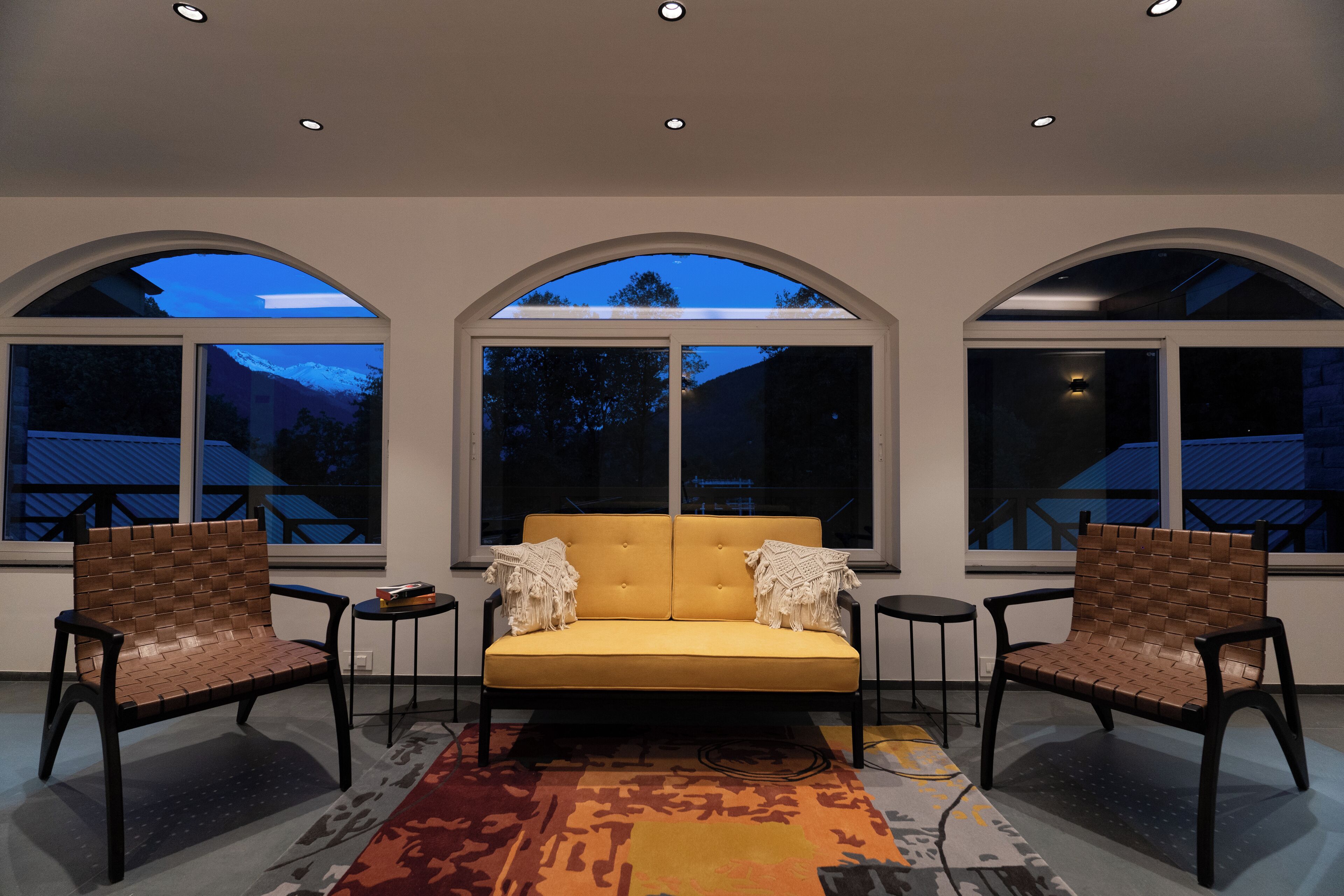 Un interior moderno con un sofá, dos sillones y una alfombra estampada.