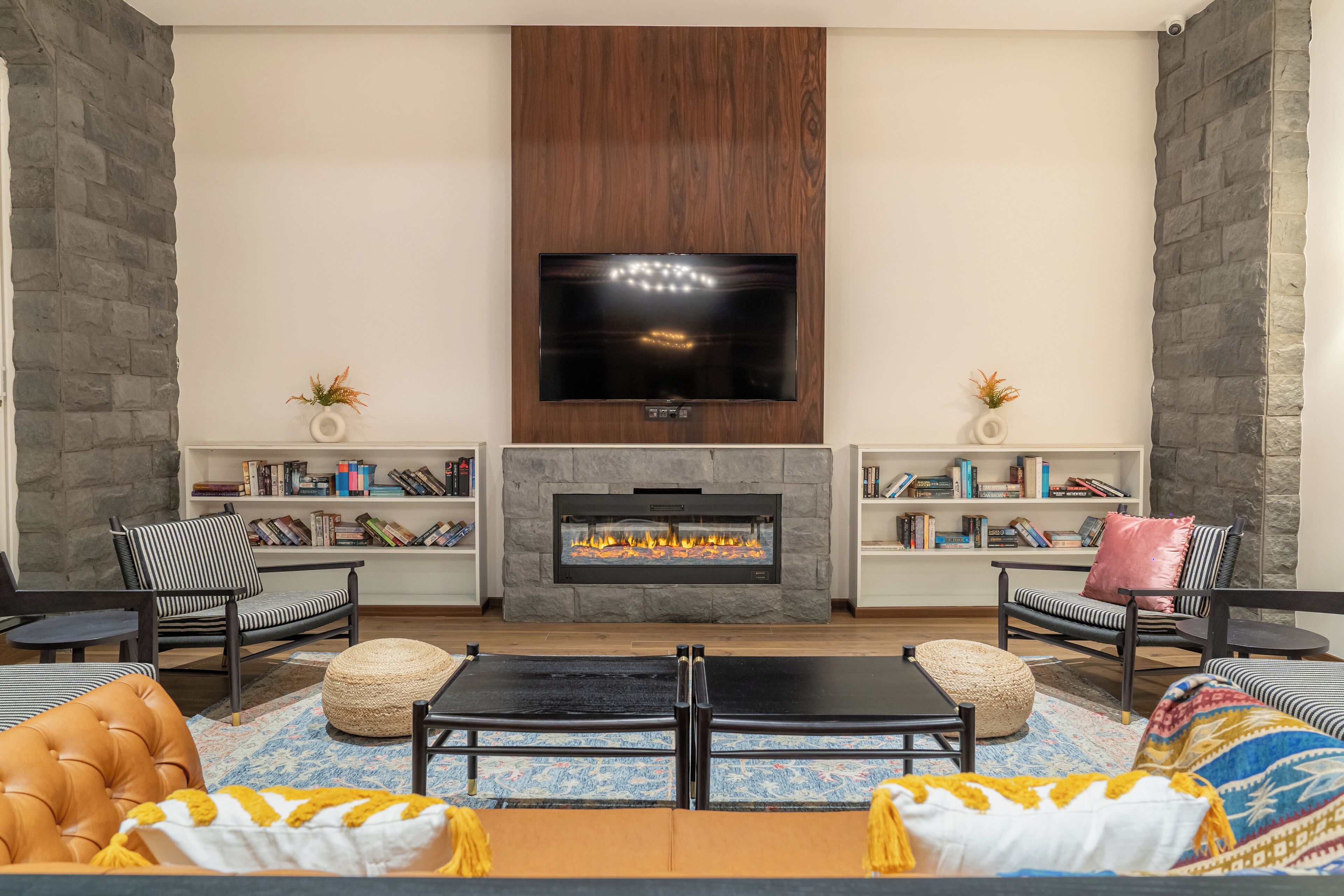 A modern living room with a fireplace, two armchairs, a sofa, and a flat-screen TV mounted above the fireplace.