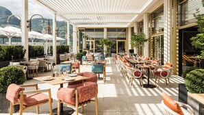 Un café extérieur spacieux, doté de nombreuses tables et chaises, de grandes fenêtres et offrant une vue sur le paysage environnant.