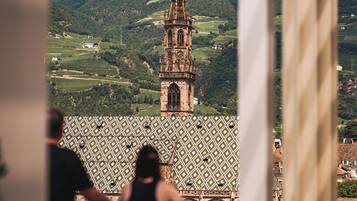 Une tour historique à l’architecture complexe, dotée d’un toit orné et offrant une vue sur des collines verdoyantes en arrière-plan.