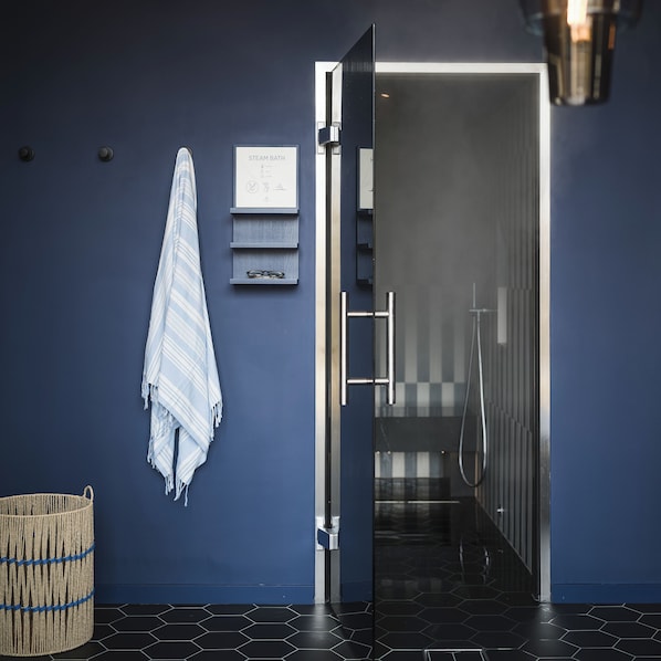 Un baño moderno con el letrero de un baño de vapor, una toalla y una cesta tejida en el suelo.