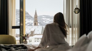 Une personne est assise près d’une fenêtre, d’où elle a vue sur une ville enneigée et sur le clocher d’une église.
