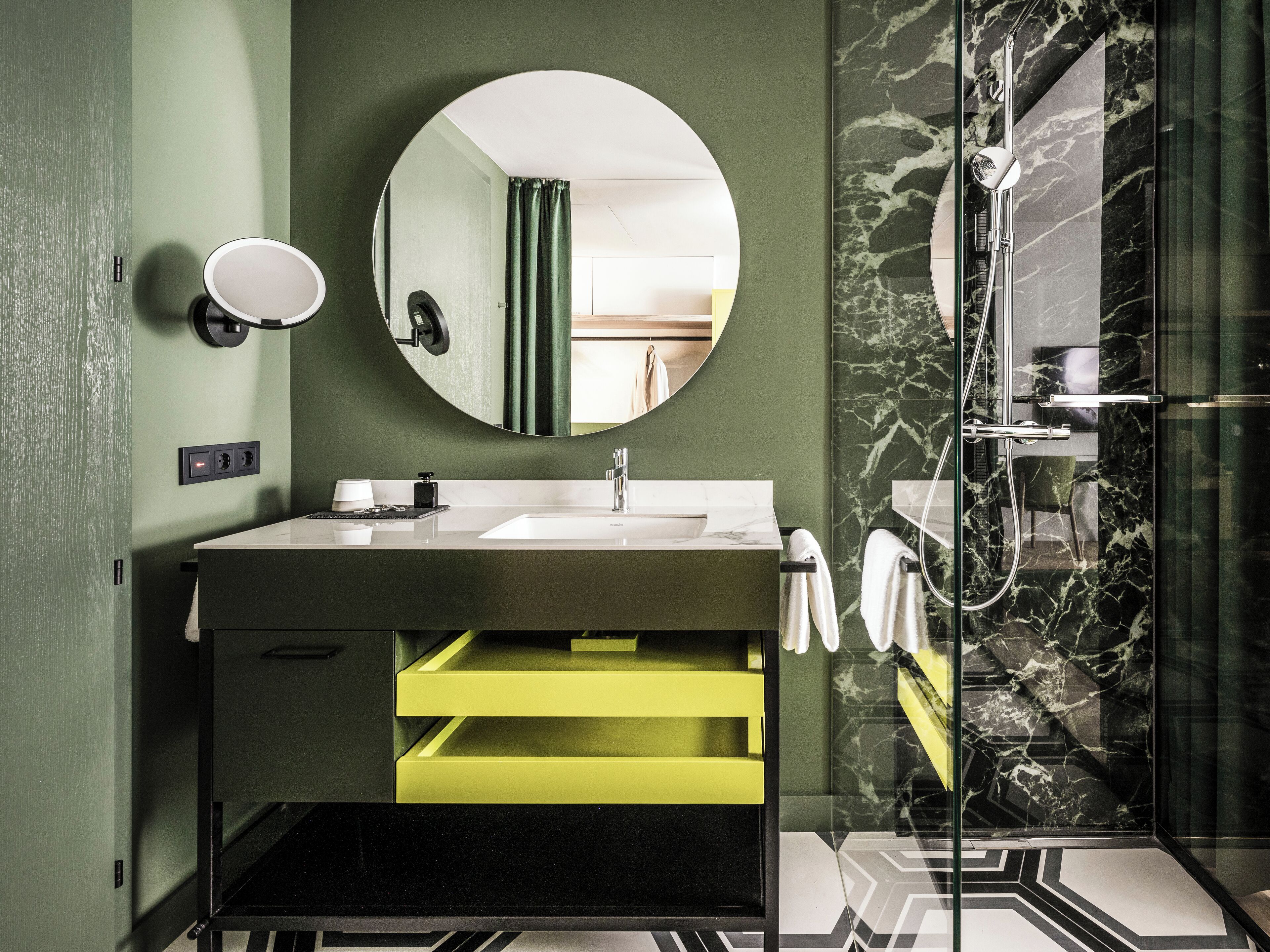 Une salle de bain moderne avec un miroir rond, un lavabo et un espace douche.