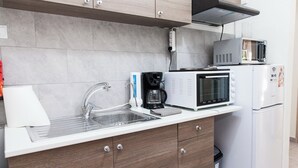 Moderni keittiö, jossa on sisäänrakennettu mikroaaltouuni, kahvinkeitin ja jääkaappi.